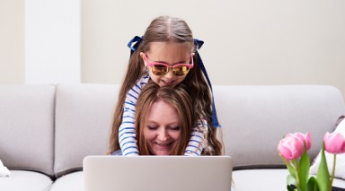Foto van moeder en dochter achter een laptop