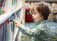 Een jongetje kiest een boek uit in de bibliotheek
