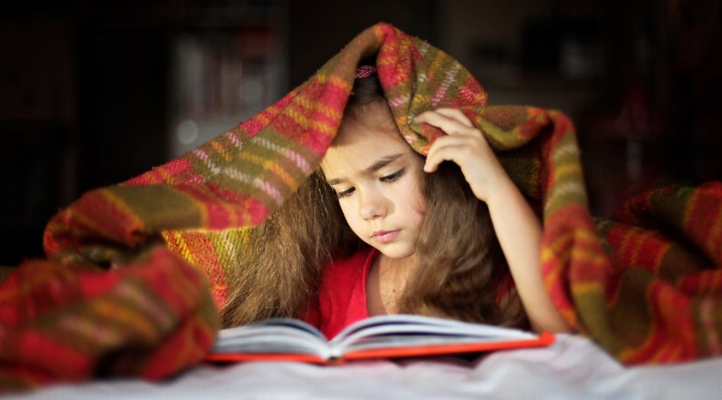 Meisje leest onder deken