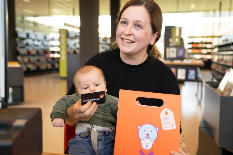 Moeder met het BoekStartkofferte, haar baby en een lidmaatschapspas van de Bibliotheek